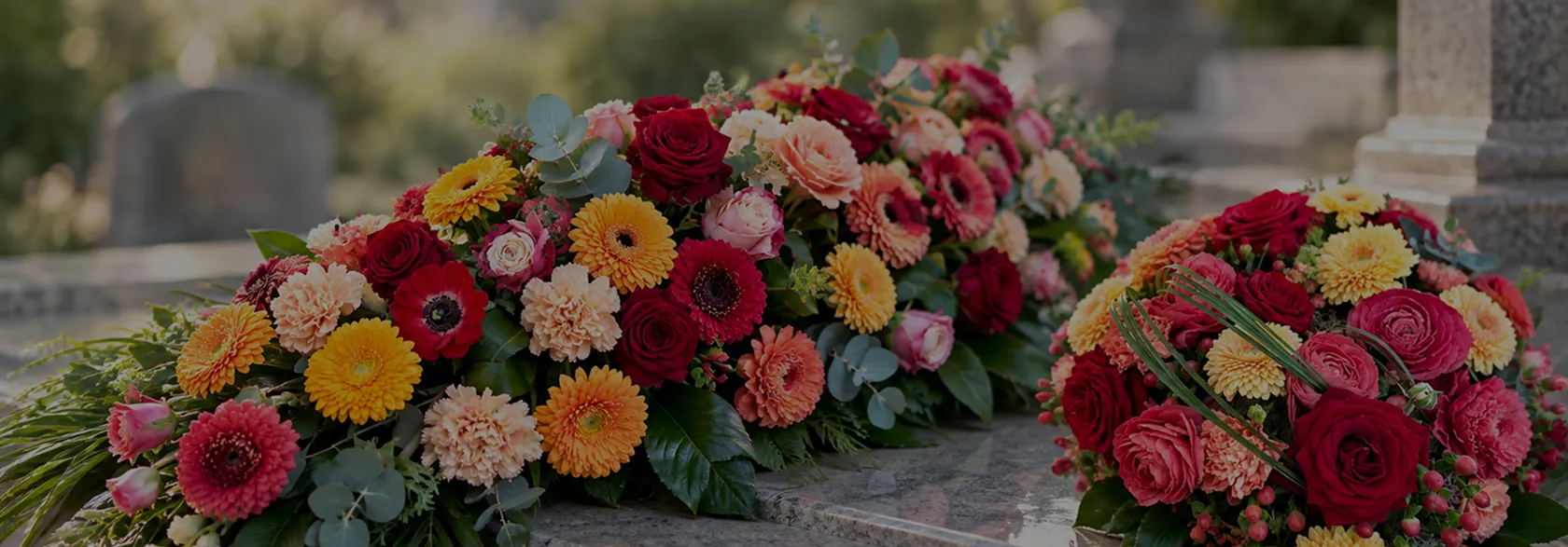 Compositions funéraires colorées de roses, gerberas et œillets posées sur une tombe